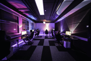 Wide view of a dimly lit gaming room with gamers at their PC stations.