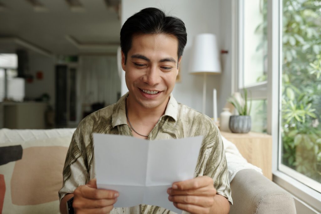 a man smiling while holding a paper